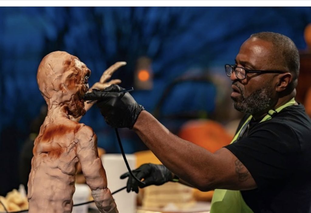 Reggie airbrushing a sculpted figure on the Halloween Wars set